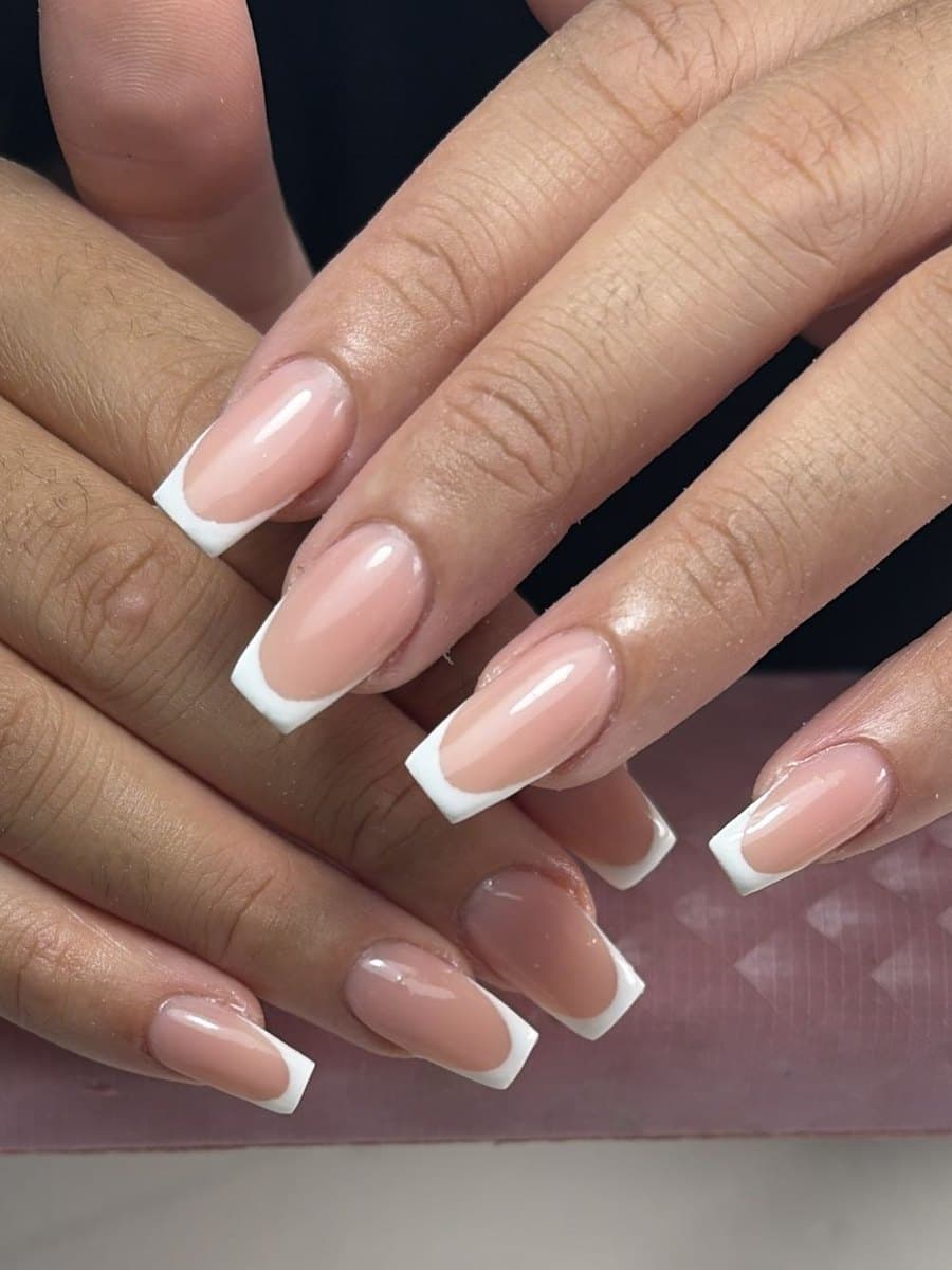 French blanche sur ongles carrés longs, pointes épaisses et nettes sur base nude, deux mains croisées