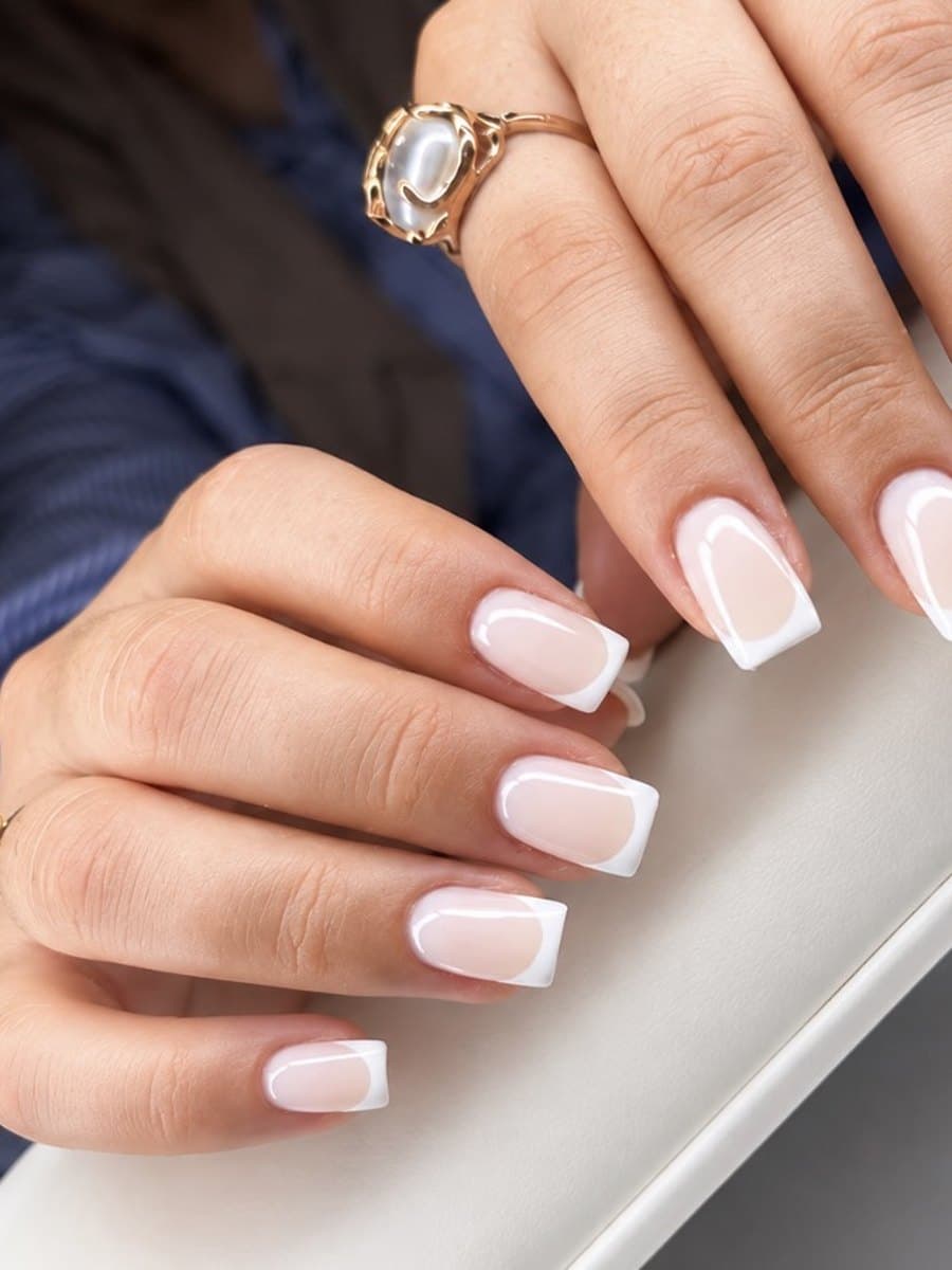 French blanche sur ongles carrés courts, pointes nettes sur base nacrée, deux mains posées l'une sur l'autre